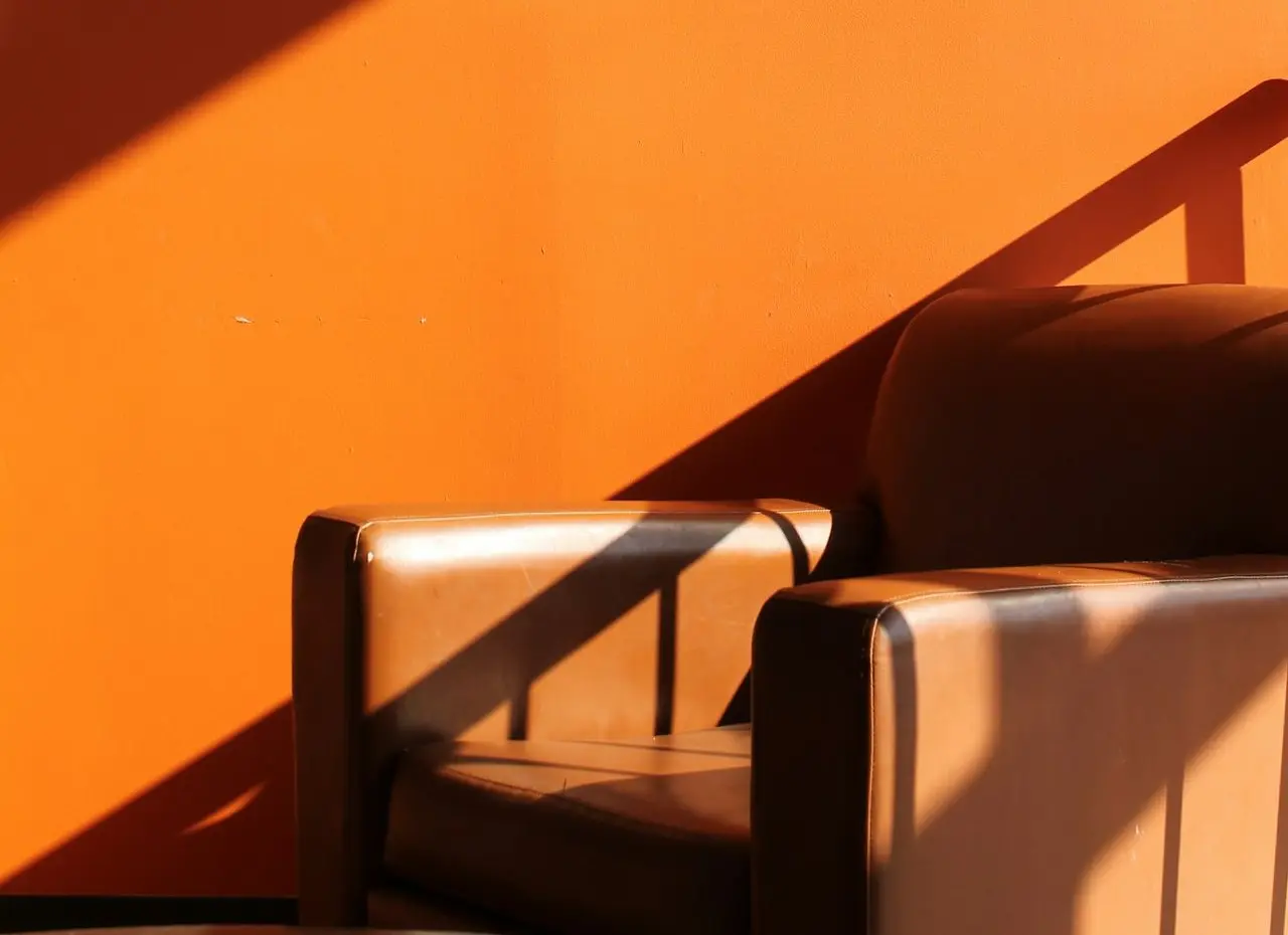 a chair sitting in front of an orange wall