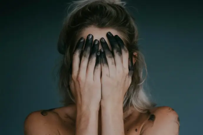 Femme épuisée se cachant le visage dans les mains, symbole du burn-out - Mitra Yoga